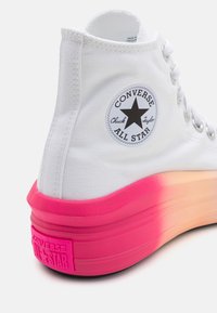 Weißer High-Top-Sneaker mit einem strukturierten Oberschuh aus Canvas, ausgestattet mit einem runden schwarzen Logo und einer dicken Sohle, die von Pink zu Orange verläuft.