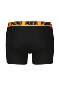 Schwarze Boxershorts mit enganliegendem Schnitt, ausgestattet mit einem breiten gelben Bund, auf dem das "PUMA"-Logo in Schwarz gut sichtbar angebracht ist.