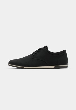 Schwarze Schnürschuhe aus glattem Textil-Obermaterial, mit niedrigem Profil, runder Zehenform und akzentueller, hellfarbiger Sohle.