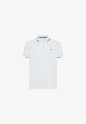 Polo blanco de manga corta con ribetes negros en el cuello y los bordes de las mangas, botones en el cuello y un pequeño logo negro en forma de triángulo y X en el pecho.
