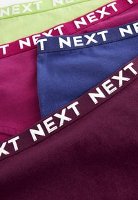 Quattro paia di slip in cotone elasticizzato verde, rosa, blu e bordeaux, con l'etichetta bianca "NEXT" sulla cintura di ciascun paio.