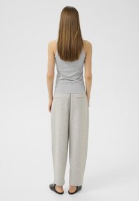 Hall hall tindiga t-särk koos heledast grisist laia säärega treeningpükstega. Riietus omab mugavat lõiget ja sileda kangatekstuuri. Mustad libiseda kingad.