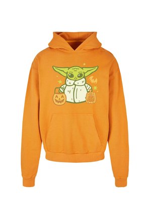 Oranžová mikina s kapucňou a vreckom, zdobená grafikou postavy držiacej tekvice a hviezdy s halloweenovou tematikou.