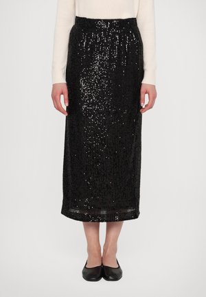 Jupe midi en sequins noirs avec une silhouette droite, taille élastique et texture lisse. Associée à des ballerines noires et un pull léger.