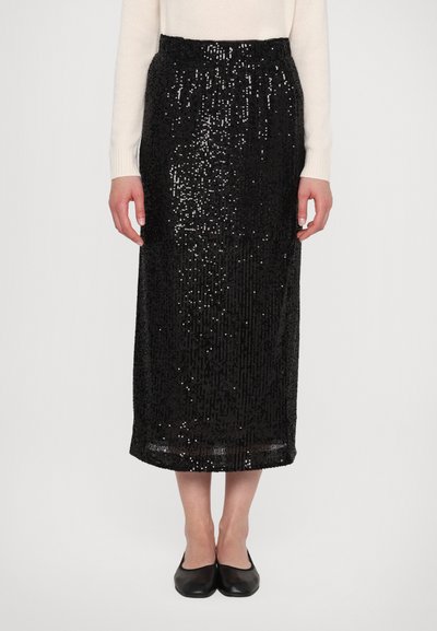 Schwarzer Pailletten-Midirock mit gerader Silhouette, elastischem Bund und glattem Textil. Kombiniert mit schwarzen Ballerinas und einem leichten Pullover.