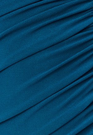 Tyrkysová texturovaná látka s záhybovým dizajnom, ktorý obsahuje jemné záhyby a mierny lesk. Materiál pôsobí ľahko a hladko.