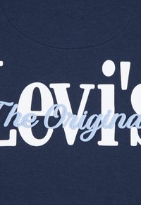 Μπλε βαμβακερό μπλουζάκι με μεγάλο λευκό και ανοιχτό μπλε κεντημένο κείμενο που γράφει "Levi's The Original." Διαθέτει στρογγυλή λαιμόκοψη.