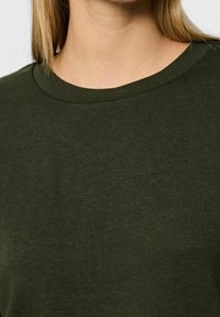 T-shirt in cotone verde oliva con collo rotondo, caratterizzato da una texture liscia e maniche corte. Il tessuto appare morbido e leggero.