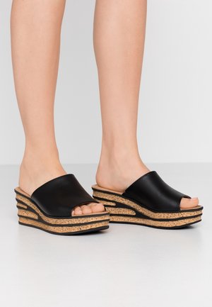 Czarne platformy sandały z otwartym palcem, z gładkim wierzchem, teksturowaną korkową podeszwą oraz warstwowym designem z zakrzywionymi wycięciami po bokach.