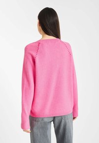 Felle roze trui met een relaxte pasvorm, ronde halslijn en ribgebreide zoom. Kenmerkt decoratieve stiksels langs de raglan-naden. Zachte textuur.