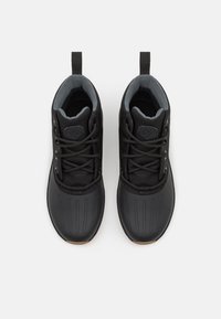 Para czarnych sneakersów na sznurówki z szarym wykończeniem wewnętrznym i uchwytami, widziana z góry na białym tle.