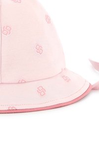 Chapeau seau rose en tissu doux avec une finition légèrement brillante. Caractérisé par des motifs de logo en relief et une bordure rose contrastante.