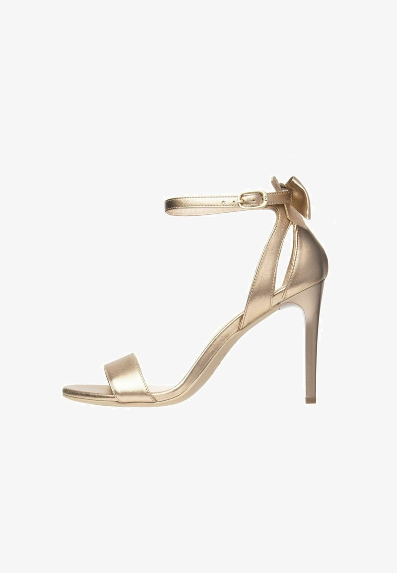 Gold metallic high-heeled sandal with a thin ankle strap, open toe, and a smooth texture. Features a delicate bow accent at the heel.