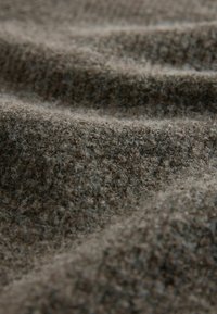 Tekstureret brun stof med en fuzzy overflade, der indeholder en blød, varm vævning og en subtil mønster. Materialet er uldlignende og tykt.