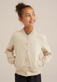 Béžová bomber bunda s rebrovaným golierom, predným zapínaním na gombíky a bočnými vreckami. Mäkká látka s hladkou textúrou.
