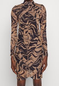 Robe mini à manches longues en tissu brun transparent avec des rayures abstraites de zèbre noires, dotée d'un col haut et de détails froncés tout au long.