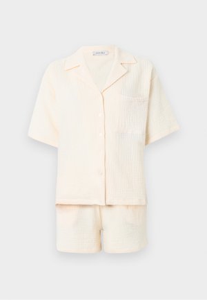 Cream-colored textured short-sleeve button-up shirt with chest pocket and matching shorts set on a plain light background.