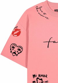 Chemise rose avec l'inscription noire « love is the answer », lèvres rouges avec « fresh kiss », un cœur qui pleure et le texte « mi amor » avec une flèche sur la manche.