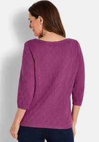Paarse gebreide top met lange mouwen, featuring een textuurpatroon, wijde halslijn en geribbelde manchetten en zoom, gecombineerd met donkere jeans.