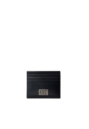 Porte-cartes en cuir noir avec quatre emplacements pour cartes et une plaque logo rectangulaire argentée portant l'inscription "CALVIN" au centre avant.