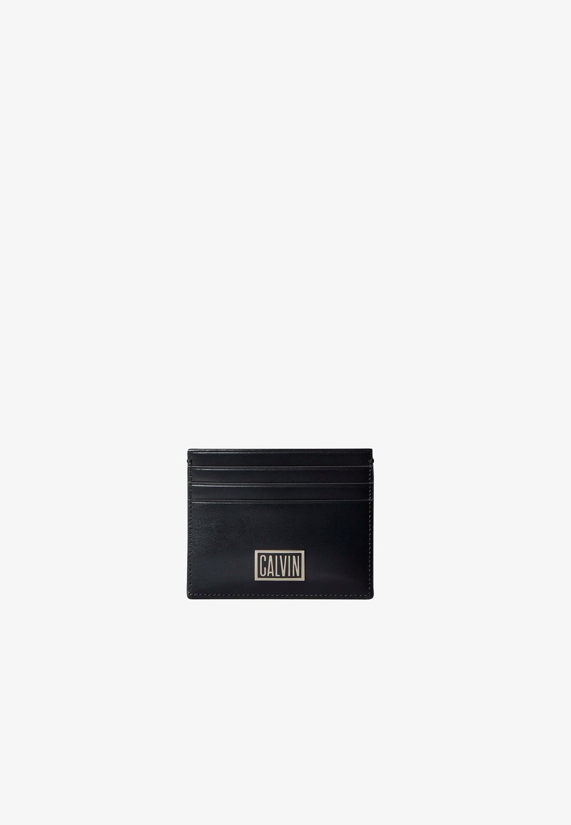 Porte-cartes en cuir noir avec quatre emplacements pour cartes et une plaque logo rectangulaire argentée portant l'inscription "CALVIN" au centre avant.