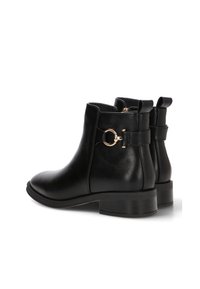 Botas de cuero negras hasta el tobillo con punta redonda, detalles en oro y un tacón bajo de bloque. Textura suave y diseño clásico.