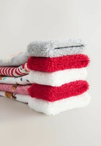Stapel von fünf Paar gemütlichen Socken in Grau, Rot und Weiß. Strukturierter, flauschiger Stoff mit verschiedenen Mustern, darunter Streifen und festliche Designs.