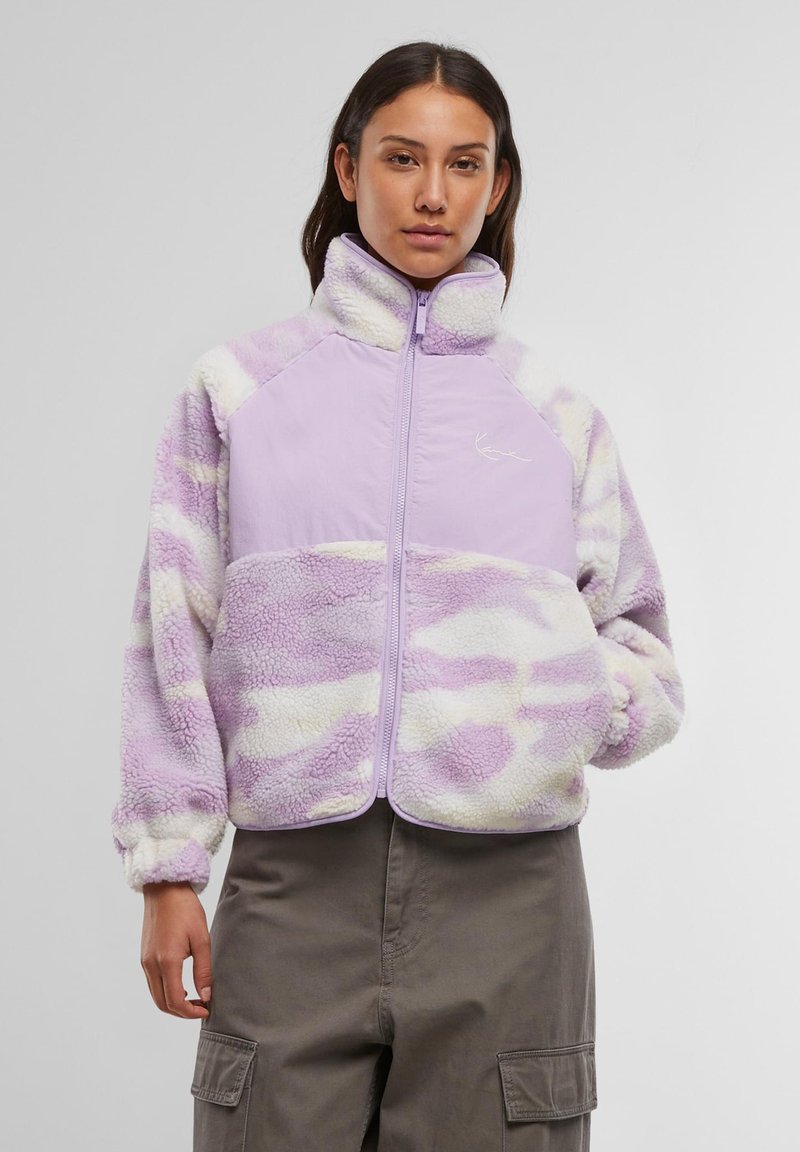 Fialová fleecová bunda so zipsom vpredu, vysokým golierom, obláčkovým vzorom vo svetlejších odtieňoch a elastickými manžetami. Výrazné logo značky na prsiach.