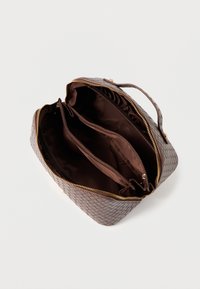 Ruda austinė rankinė su tekstūruotu išoriniu paviršiumi, auksinėmis užtrauktukais ir dviem atskiromis skyreliais, išklotais tamsia medžiaga.