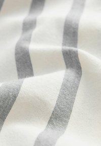 Tissu en coton présentant des rayures alternées blanches et gris clair, avec une texture douce et un motif de tissage subtil.