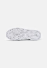 White rubber sneaker sole with herringbone pattern, circular accent, and brand name "LACOSTE" embossed near the heel.