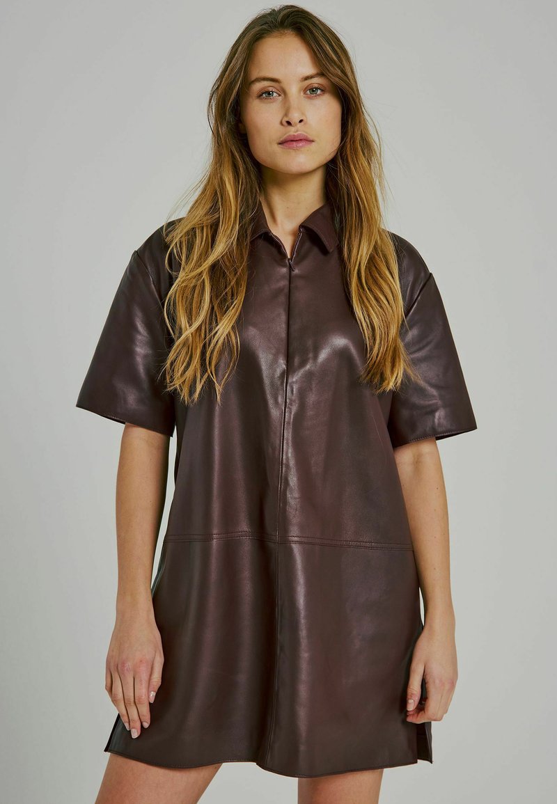 Abito camicia in pelle marrone con maniche corte, colletto e design pulito. Presenta una chiusura frontale con bottoni e orlo dritto.