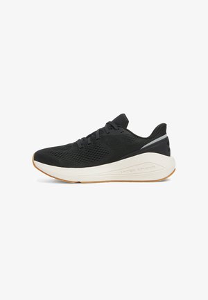 Chaussure de sport noire avec une tige en maille texturée, une semelle intermédiaire blanche rembourrée et une semelle extérieure en caoutchouc. Présente un petit accent réfléchissant au niveau du talon.