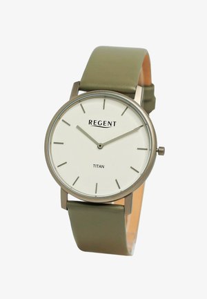 Montre Titan avec un boîtier rond en acier inoxydable, un cadran blanc, des index heures minimalistes et un bracelet en cuir vert. Nom de la marque "REGENT" affiché.