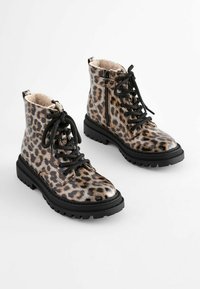Bottines à imprimé léopard avec surface brillante, lacets noirs, intérieur texturé et semelle en caoutchouc contrastante avec motif de semelle.