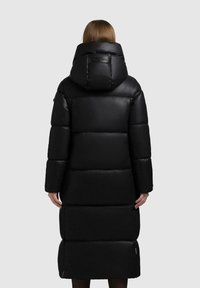 Sort puffjakke med hætte, der har et quiltet design, lange ærmer og en knælængde. Glat tekstur og minimal branding.