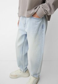 Lyseblå baggy jeans med høj talje, lavet af denim, med blød tekstur og et klassisk fem-lomme design, parret med hvide sneakers.