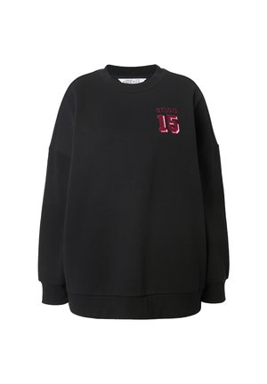 Sweatshirt noir avec un col rond, coupe ample, épaules tombantes, et un "STUDIO 15" brodé bordeaux sur le devant. Matière en coton doux.