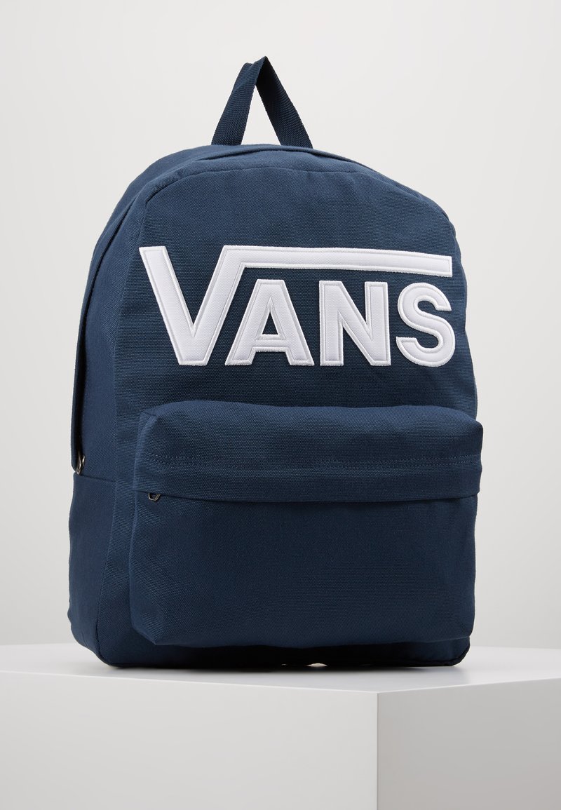 Zaino di stoffa blu con grande logo bianco "VANS", tasca frontale e manico superiore per il trasporto. Tessuto testurizzato con cuciture resistenti.