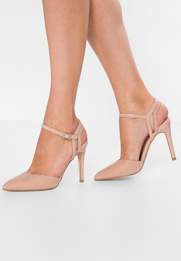 Nudet korkokengät, joissa on terävä nilkka, valmistettu sileästä materiaalista. Varustettu nilkkahihnalla ja soljella sekä kapealla stiletto-korkolla.