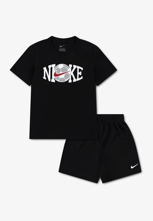 Camiseta negra de manga corta de Nike con un balón de fútbol y un logo swoosh rojo, combinada con pantalones cortos negros que tienen un logo swoosh blanco.