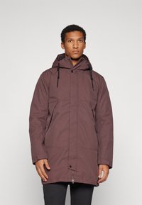 Parka rouge bordeaux avec capuche, fermeture éclair et deux poches avant, au toucher lisse et cordons de serrage réglables.