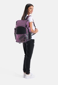 Zaino viola con dettagli neri, tasca in rete, più scomparti e dettaglio logo. Cinghie regolabili per un comfort ottimale.