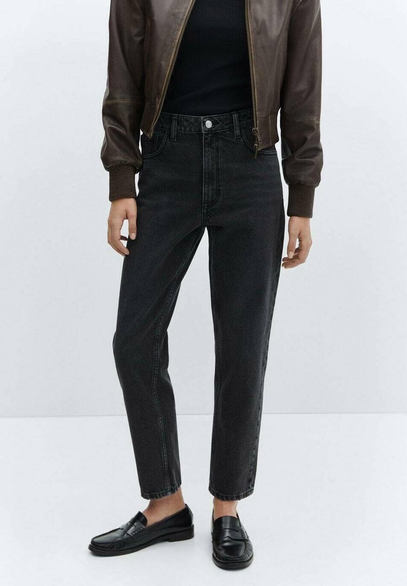 Jean en denim noir à taille haute et jambes fuselées, associé à une veste bomber en cuir marron et des mocassins noirs. Texture lisse, détails minimalistes.