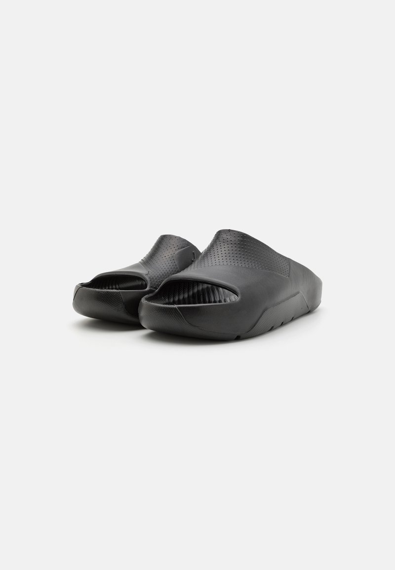Scarpe nere senza lacci con un design open toe, superficie testurizzata e finitura opaca liscia. Presentano perforazioni per la traspirabilità.