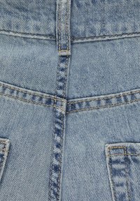 Ljusblå denimtyg med en central söm, två bakfickor och kontrasterande beige sömnad längs sömmar och fickor.