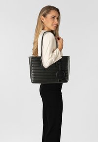 Schwarze Kunstleder-Shopper-Tasche mit strukturierten vertikalen Streifen, doppelten Schulterriemen und einem runden abnehmbaren Münzgeldbeutel.