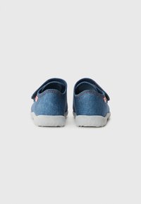 Blå denim slip-on skor med en vadderad krage, utrustade med en kardborreband och en gummisula med texturerat greppmönster.