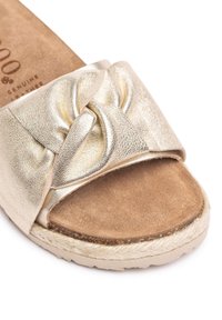 Gold metallic slide sandal with a knotted strap design and soft suede insole, featuring an espadrille-style woven midsole and rubber outsole.