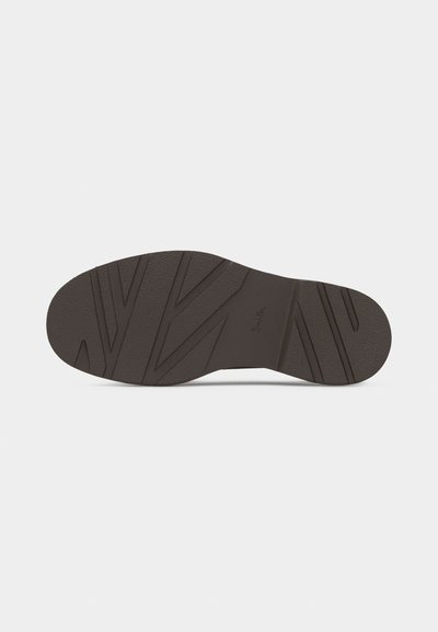 Σόλα σκουρόχρωμου καφέ παπουτσιού με υφή, γωνιώδεις αυλακώσεις και μικρό ανάγλυφο λογότυπο στο κέντρο πάνω σε απλό φόντο.